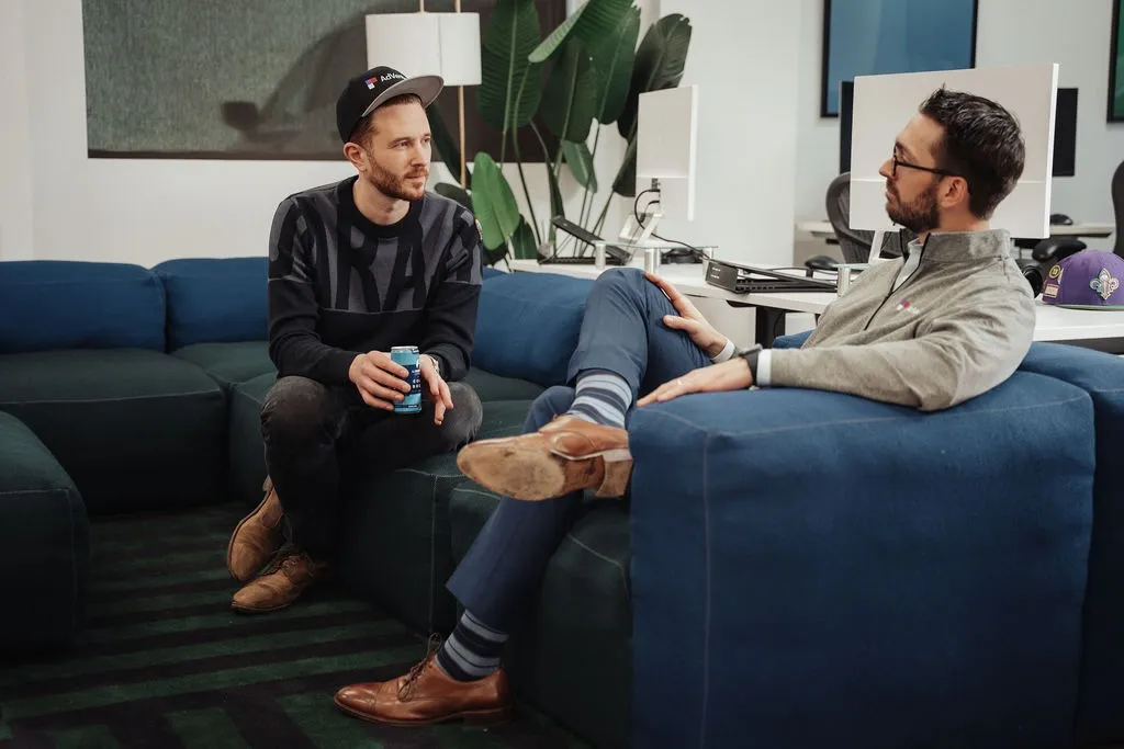 Two AdVenture Media team members having a casual conversation on a couch in the New York office